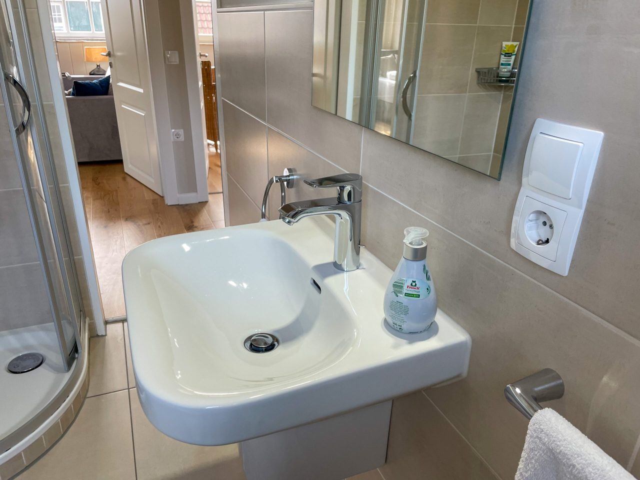 Badezimmer mit Glasdusche, Waschtisch, WC, Kosmetikspiegel und Fön
