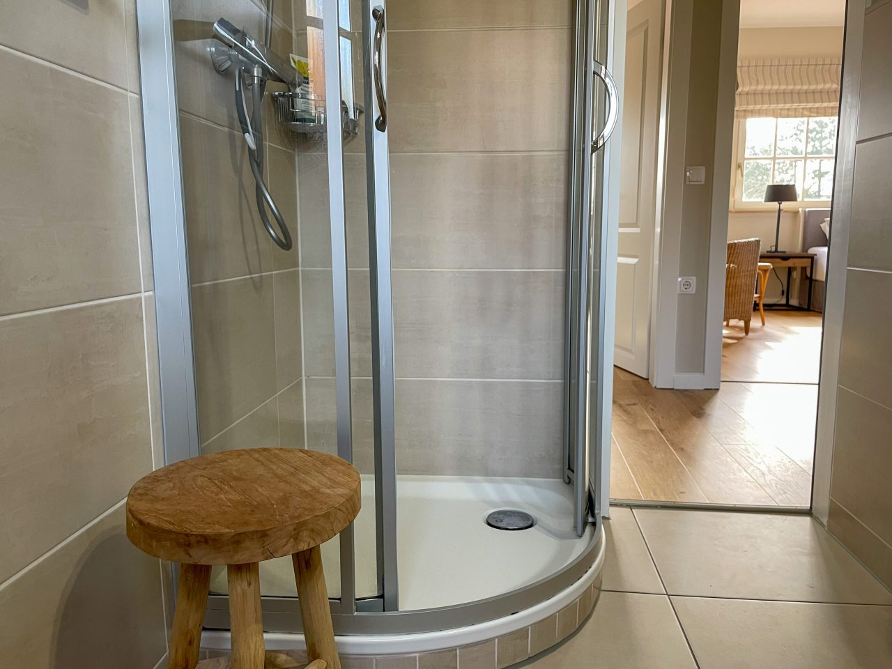 Badezimmer mit Glasdusche, Waschtisch, WC, Kosmetikspiegel und Fön
